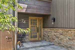 Entrance to property with stone siding and a patio