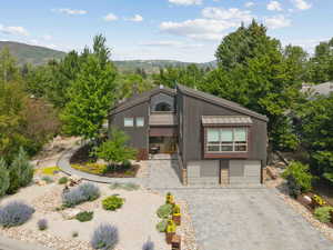Mid-century modern home with a metal roof, a standing seam roof, decorative driveway, an attached garage, and a mountain view