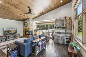 Living room featuring recessed lighting, wet bar, wine cooler, wooden ceiling, and a multi sided fireplace