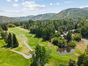 Aerial overview of property's location featuring a golf club and a water and mountain view