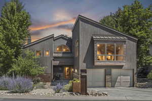 View of front of house with stone siding, a standing seam roof, a balcony, driveway, and a metal roof