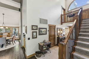 Stairs featuring a high ceiling, wood-type flooring, and a chandelier