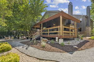 Rear view of house with a chimney, covered porch, a metal roof, and stairway
