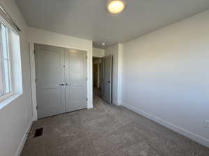 Unfurnished bedroom featuring carpet and a closet