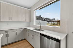 Kitchen with dishwasher, decorative backsplash, light wood finished floors, light stone counters, and a residential view