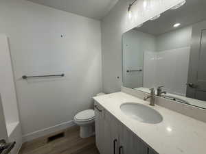 Full bath featuring dark wood-style floors, vanity, and washtub / shower combination