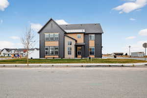 View of front facade featuring roof with shingles, a front lawn, and brick siding
