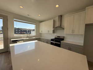 Kitchen featuring dark wood finished floors, stainless steel appliances, wall chimney range hood, recessed lighting, and decorative backsplash