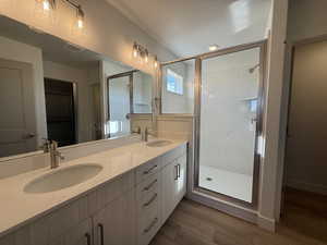 Bathroom featuring a shower stall, double vanity, dark wood-style flooring, a walk in closet, and recessed lighting