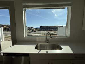 Kitchen featuring dishwasher, a residential view, light stone countertops, and tasteful backsplash