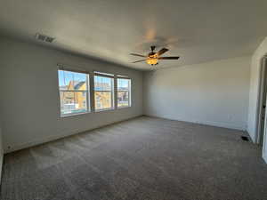 Empty room featuring light carpet, a textured ceiling, and a ceiling fan