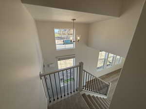 Stairway with a towering ceiling, a chandelier, a textured ceiling, and carpet