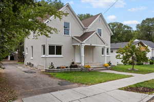 View of front facade with a shingled roof, stucco siding, and a front lawn