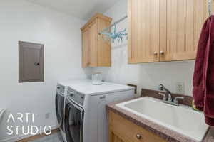 Laundry room with electric panel, washer and clothes dryer, and cabinet space