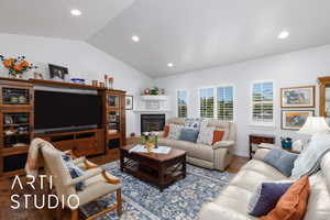 Living room with vaulted ceiling, a glass covered fireplace, wood finished floors, and recessed lighting