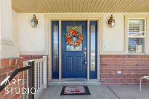 View of exterior entry featuring a porch and brick siding