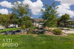 View of grassy yard featuring a patio, a playground, and a balcony