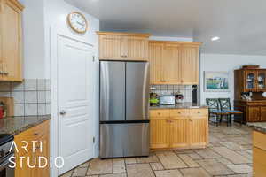 Kitchen with backsplash, freestanding refrigerator, light brown cabinets, and recessed lighting