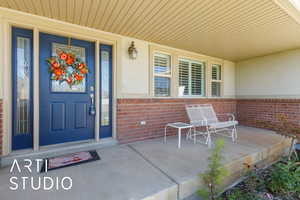 Property entrance featuring brick siding and a porch