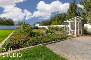 Fenced backyard featuring an exterior structure, a sunroom, and an outbuilding
