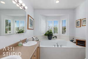 Bathroom featuring a garden tub, double vanity, and recessed lighting