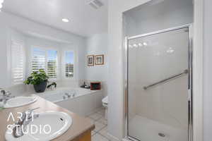 Full bath featuring light tile patterned flooring, a stall shower, a garden tub, double vanity, and recessed lighting