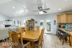 Dining space featuring recessed lighting, stone tile floors, a glass covered fireplace, ceiling fan, and lofted ceiling
