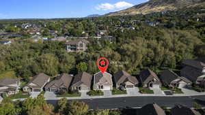 Aerial view of property and surrounding area featuring nearby suburban area and a mountain backdrop