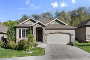 View of front of home featuring stone siding, roof with shingles, and a garage