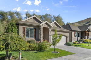 View of front of house with stone siding, stucco siding, a garage, and driveway