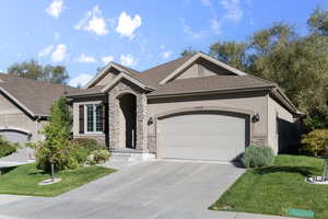 Ranch-style house with stone siding, stucco siding, an attached garage, and driveway