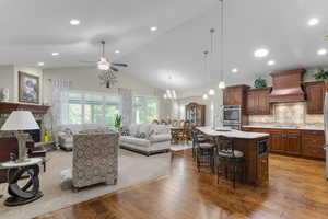 Kitchen with open floor plan, light wood-style floors, tasteful backsplash, an island with sink, and a breakfast bar