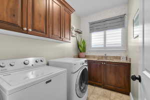 Laundry area with cabinet space, washer and dryer, and light tile patterned floors
