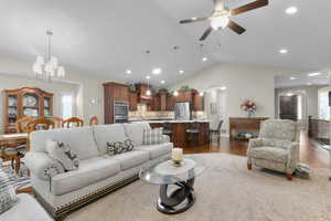 Living area featuring arched walkways, a chandelier, lofted ceiling, light wood-style flooring, and recessed lighting