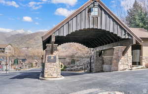 View of asphalt road with a mountain view, a gated entry, and a gate