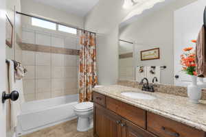 Bathroom featuring shower / bath combo with shower curtain, vanity, and light tile patterned floors