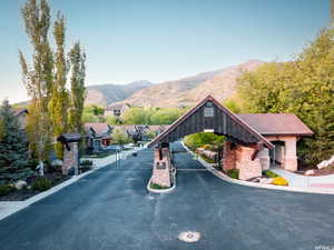 View of asphalt road featuring a gate, a mountain view, curbs, and a gated entry