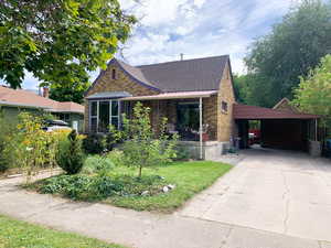 View of front of home featuring brick siding, driveway, an attached carport, roof with shingles, and a front yard