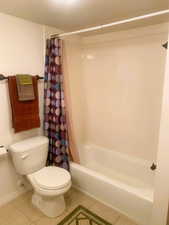 Full bath with shower / bathtub combination with curtain and tile patterned floors