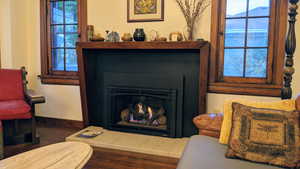 Living area with a warm lit fireplace and dark wood-style flooring