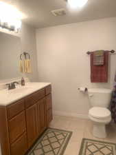 Bathroom with vanity, light tile patterned floors, and a textured ceiling