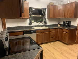 Kitchen with dark countertops, white appliances, brown cabinets, and light wood finished floors