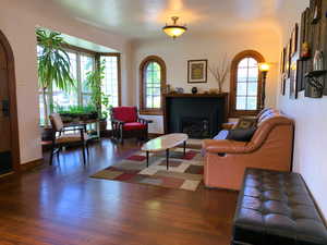 Living room with a glass covered fireplace, wood finished floors, and arched walkways