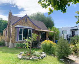 View of front of house featuring brick siding, a chimney, and a front lawn