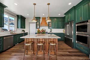 Kitchen with green cabinets, stainless steel appliances, light stone countertops, glass insert cabinets, and tasteful backsplash