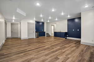 Unfurnished living room featuring dark wood-type flooring, recessed lighting, and stairs