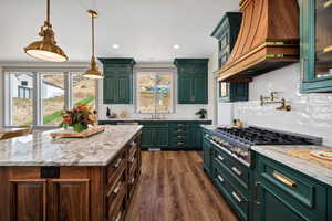 Kitchen with green cabinetry, decorative backsplash, light stone counters, stainless steel gas stovetop, and recessed lighting