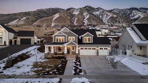 View of front of property with a porch, concrete driveway, a mountain view, and stone siding