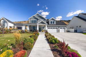 Craftsman-style house with stone siding, covered porch, driveway, and a front yard