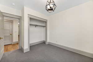 Unfurnished bedroom with light carpet, a closet, and a chandelier